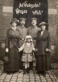 Zwei Soldaten, zwei Frauen mit Kind vor schwarzer Tafel mit Aufschrift Auf Wiedersehen Wesel