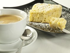 Kuchen auf schwarzem Teller und Kaffee in weißer Tasse