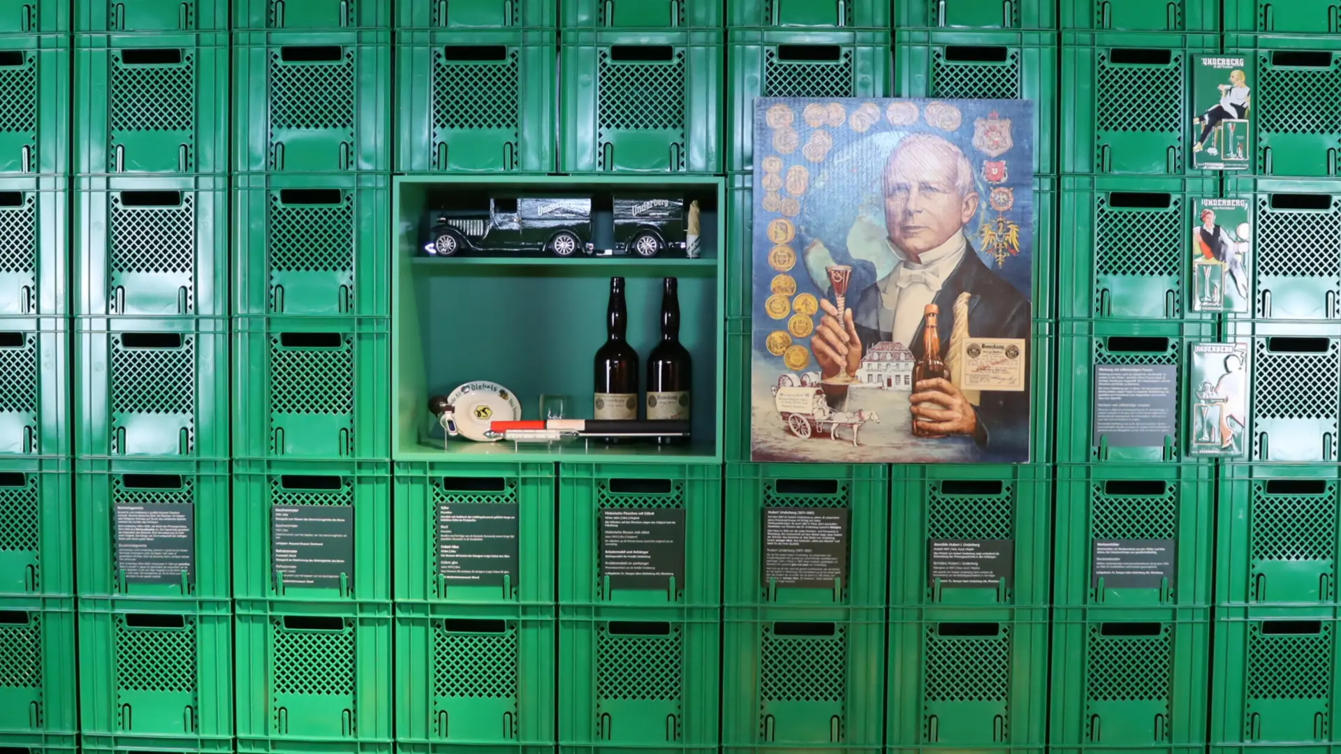 Eine Wand aus vielen übereinandergestapelten Kisten mit einem Bild, Flaschen und einem Modellauto in der Mitte der Wand