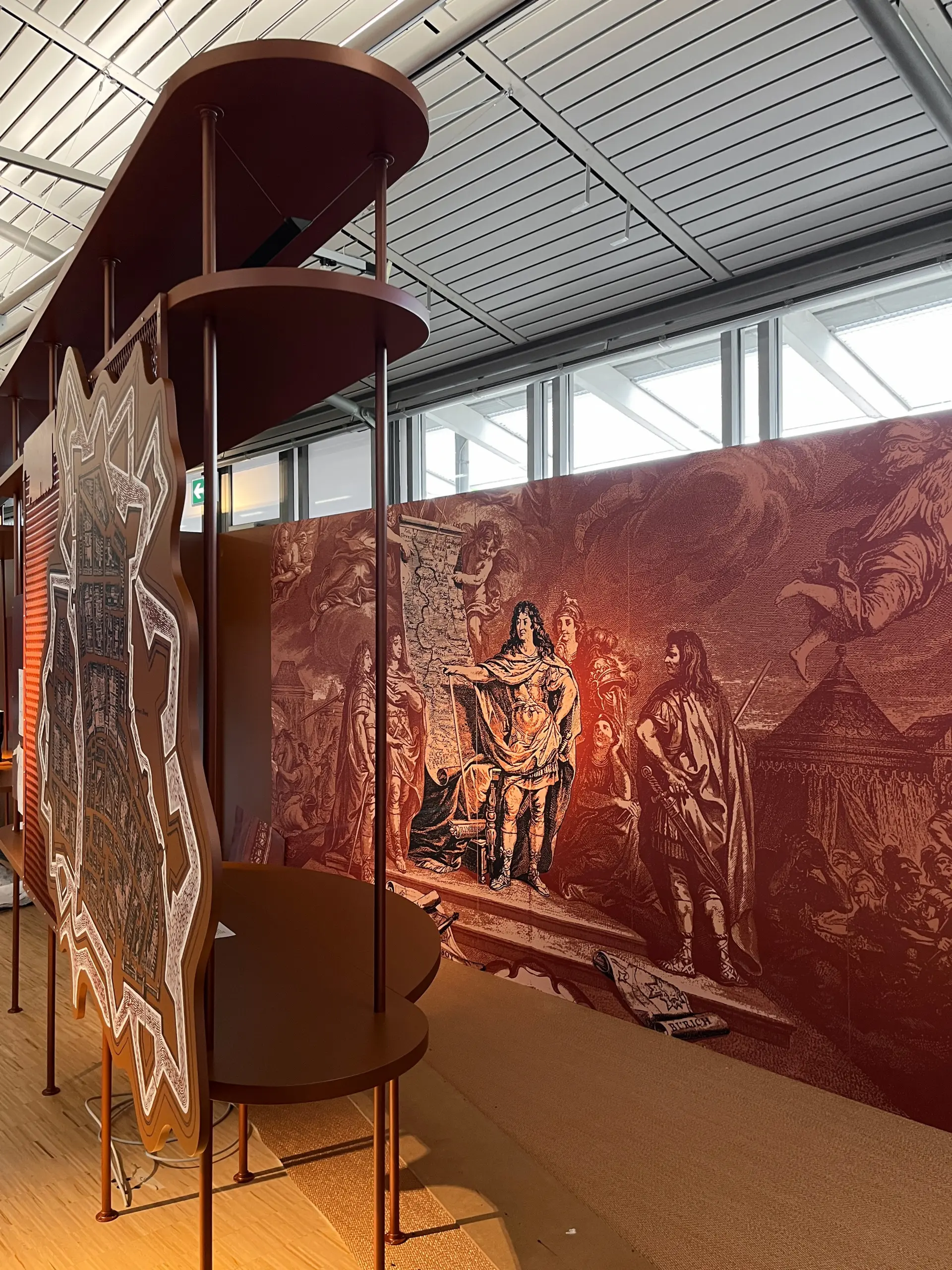 Ein Bild zeigt Männer im historischen Kontext, vor dem Gemälde stehen zwei Regale an denen eine Karte befestigt ist